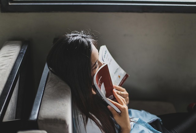 Person enjoying a quiet moment by a window with a book, highlighting personal leisure.