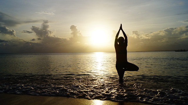 Person practicing yoga in a serene setting, symbolizing Aura Flow's mindful living journeys.